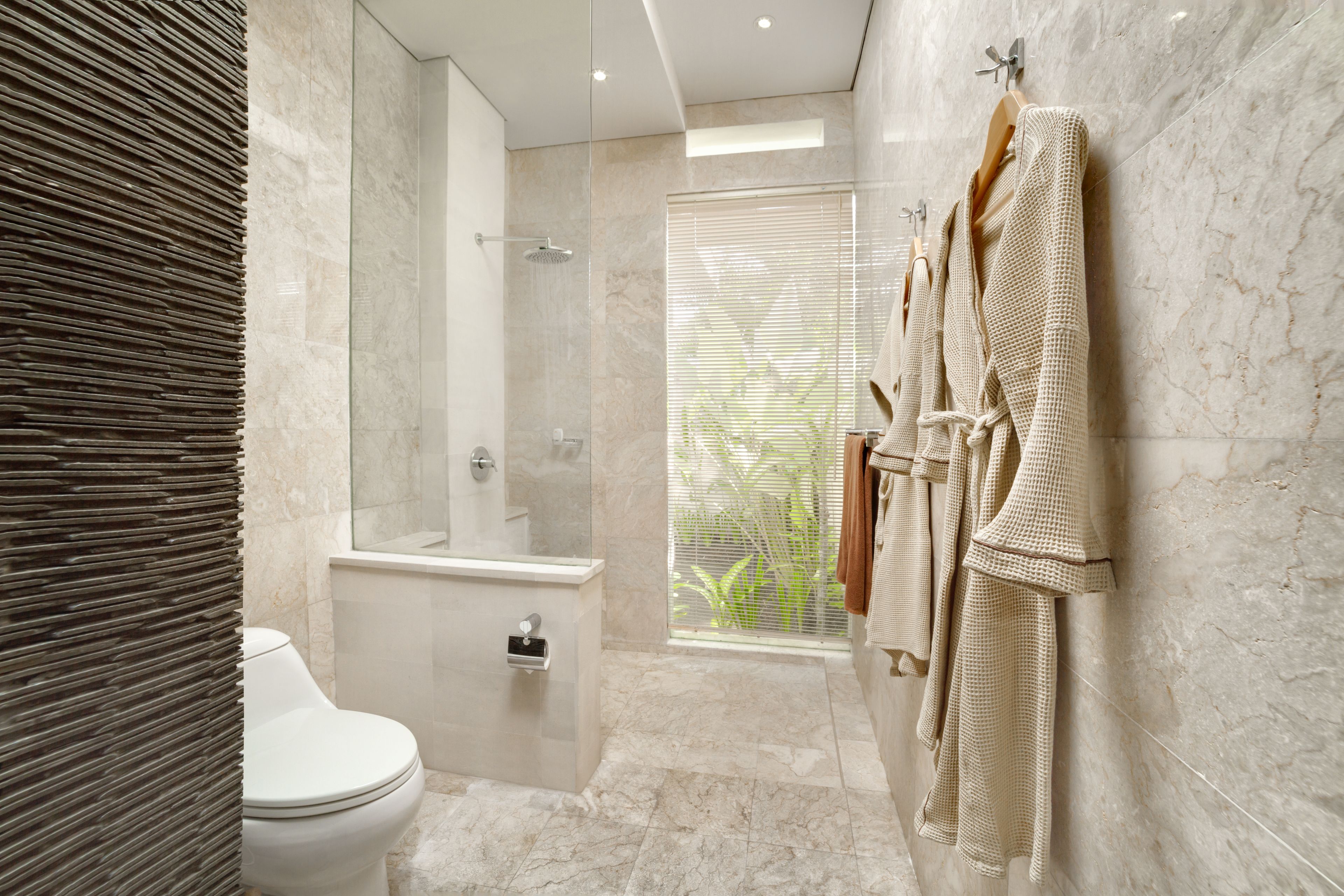 A modern bathroom with a glass-enclosed shower, a toilet, and a large mirror.