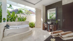 A modern bathroom with a freestanding bathtub, a vanity with a sink, and a large mirror. - D&G Villas (Nusa Dua)