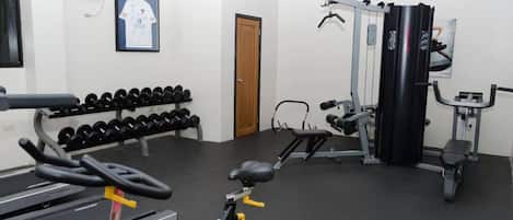 A gym with dumbbells, a bench press, and a squat rack.