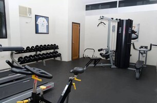 Une salle de sport équipée d’haltères, d’un banc de développé couché et d’un support à squats.