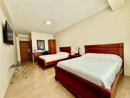 Habitación de hotel con dos camas, un escritorio, una silla, un televisor y una puerta.