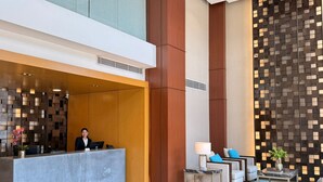 A modern hotel lobby with a reception desk, seating area, and decorative wall panels. - Hotel Marcelius (Guayaquil)