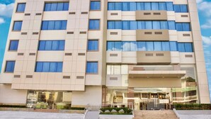 A modern hotel with a symmetrical facade, large windows, and a central entrance with a glass canopy. - Hotel Marcelius (Guayaquil)