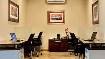 A conference room with four desks, two air conditioning units, and framed artwork on the walls.