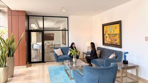A modern interior with two blue sofas, a glass coffee table, and a painting on the wall. - Hotel Marcelius (Guayaquil)
