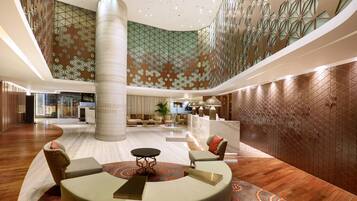 A spacious lobby with a central column, seating area, and patterned walls.