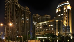 A multi-story hotel with a modern design, featuring a prominent curved facade and illuminated signage.