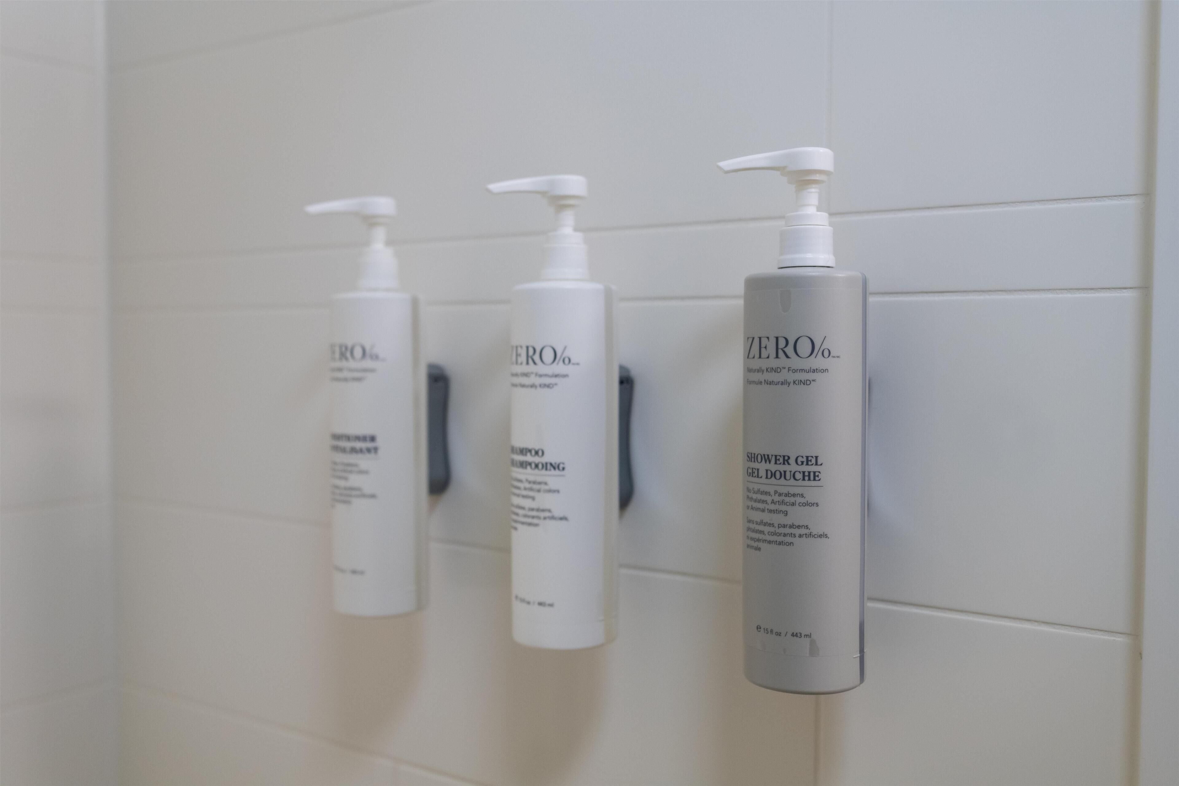 Three bottles of ZERO% shower gel on a white tiled wall.