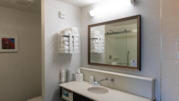 Un baño moderno con un lavamanos blanco, un espejo grande y toallas ordenadas.