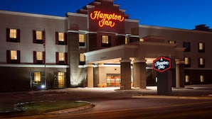 Un hotel Hampton Inn con un llamativo letrero de neón, fachada de ladrillo y una entrada bien iluminada.
