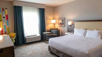 A hotel room with a large bed, a desk, a chair, a lamp, and a window with curtains.