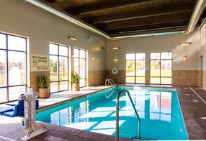 Piscina interior con señalización clara, ventanas y una silla para salvavidas.