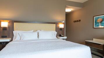 Een hotelkamer met een groot bed, twee nachtkastjes, een nachtlampje en een wandlamp.