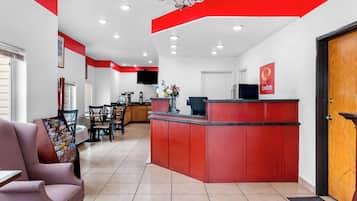 Zona de recepción con mostrador rojo, televisor y cartel que dice 'Email Lounge'.