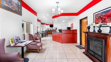 A hotel lobby with a reception desk, seating area, and a fireplace.