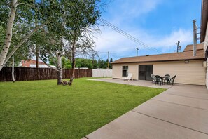 A backyard with a lawn, a wooden fence, a tree, and a building with a door and a window. - Econo Lodge Panguitch Near Bryce Canyon (Panguitch)