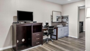 A modern hotel room with a dark wooden desk, a flat-screen TV, a chair, a small kitchenette, and a large mirror. - Econo Lodge Panguitch Near Bryce Canyon (Panguitch)