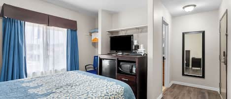 Ein Hotelzimmer mit einem Bett, einem Schreibtisch mit Computer, einem Fernseher und einem Spiegel.