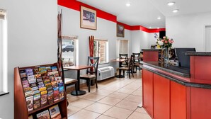 A reception area with a red counter, multiple seating options, and a travel information display. - Econo Lodge Panguitch Near Bryce Canyon (Panguitch)