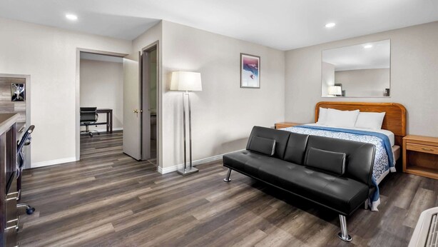 A hotel room with a bed, a black leather sofa, a desk, and a lamp. - Econo Lodge Panguitch Near Bryce Canyon (Panguitch)