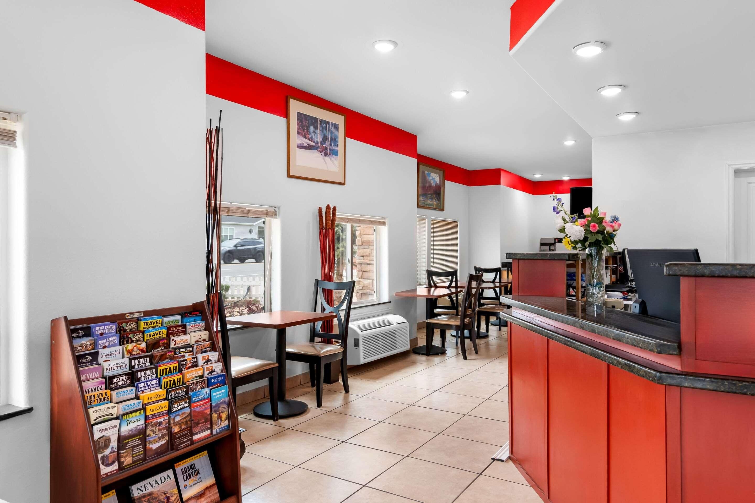 A reception area with a red counter, multiple seating options, and a travel information display.