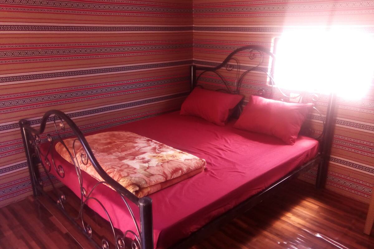 A room with a bed, a chair, and a window.