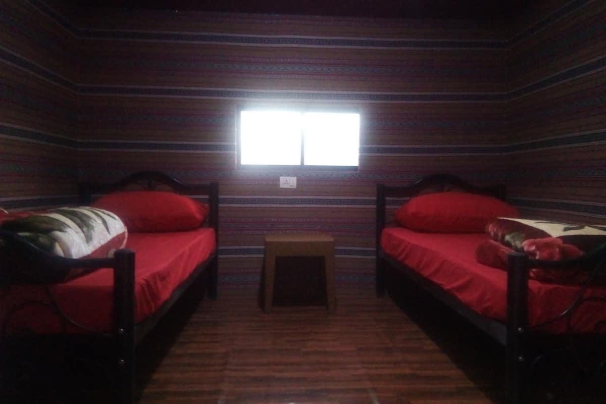 A room with two beds, a small table, and a window.