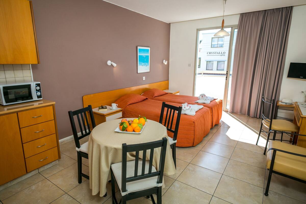 Habitación de hotel con cama, una mesa de comedor con sillas, microondas y vista al exterior.