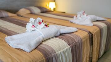 Habitación de hotel con dos camas, cada una con una toalla doblada y una orquídea blanca.