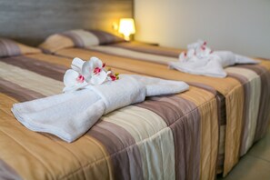 A hotel room with two beds, each with a neatly folded towel and a white orchid. - Crystallo Apartments (Paphos)