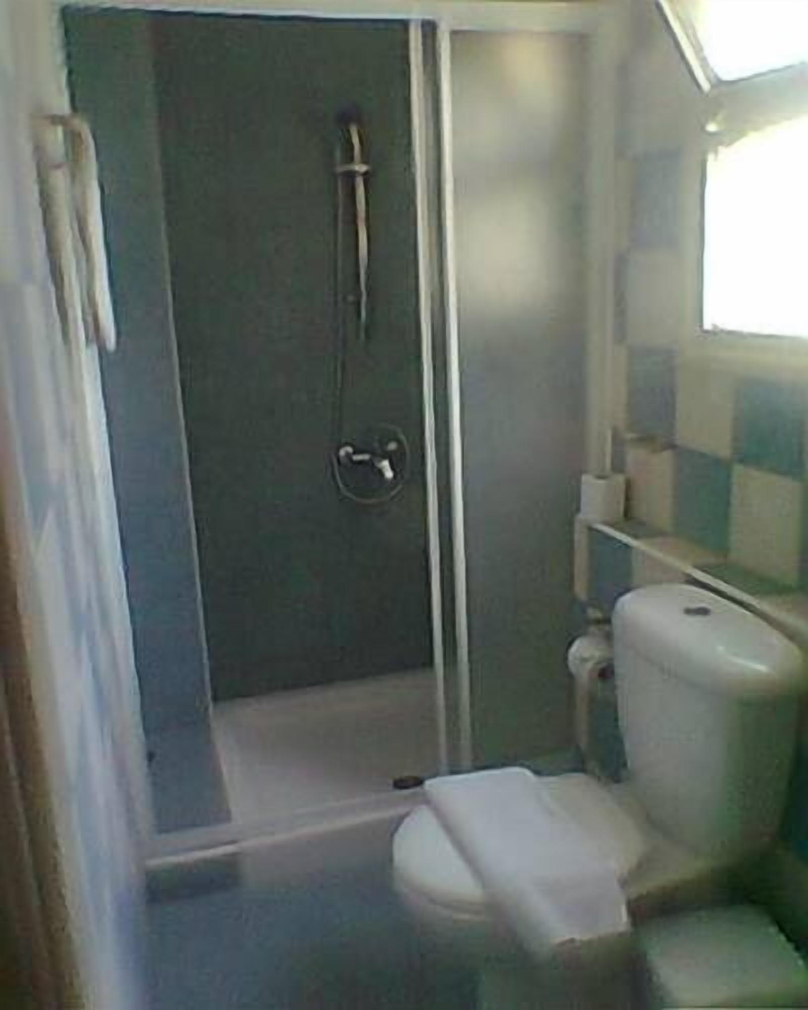 Une petite salle de bain avec des toilettes, une douche et un lavabo.