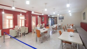 A dining area with tables and chairs, a blue rope barrier, and a red wall. - Light House - Old City (Tbilisi)