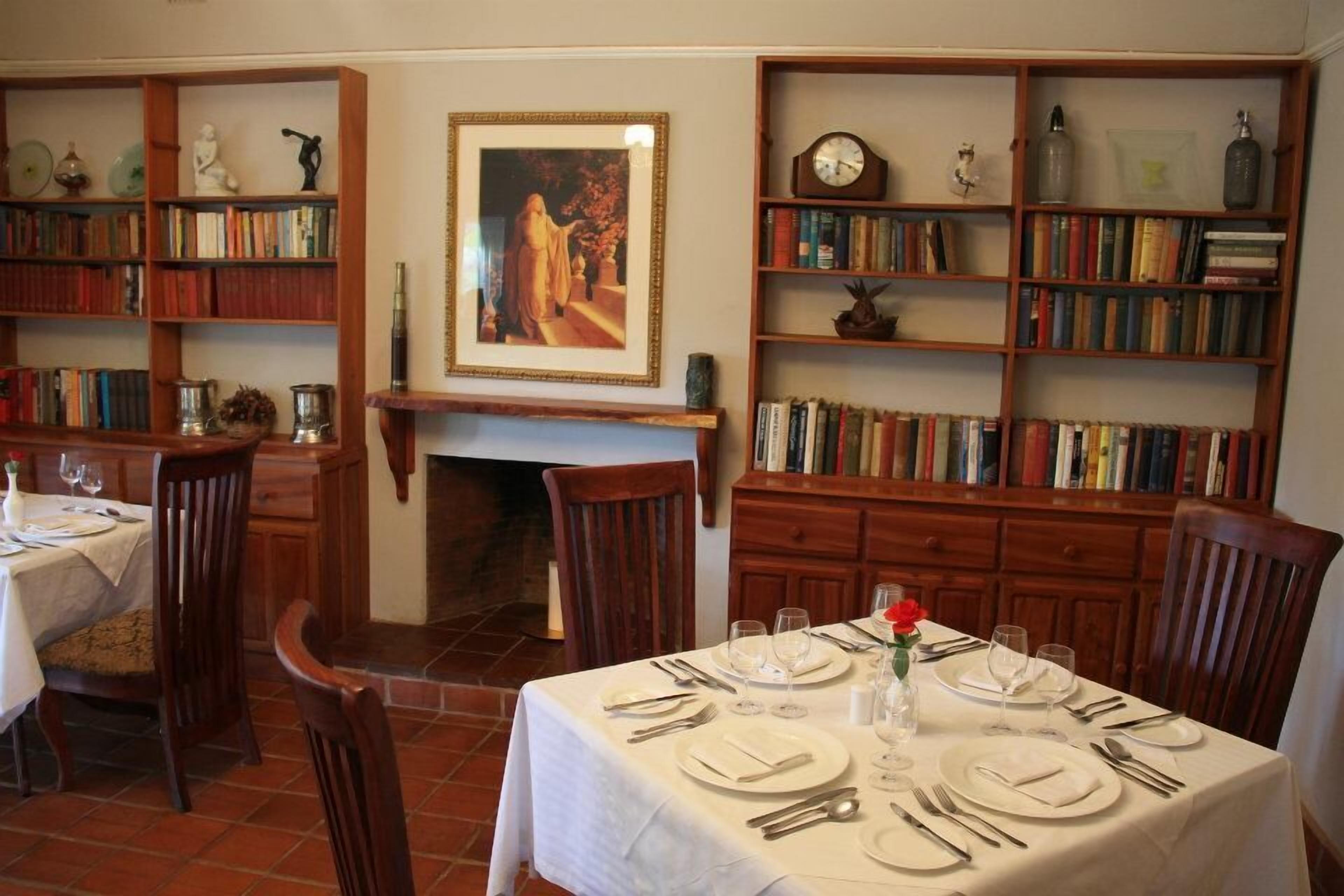 A dining room with a fireplace, wooden bookshelves, and a table set for four.