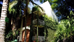 A hotel with a white exterior, surrounded by lush greenery and palm trees.