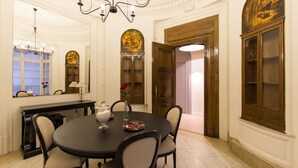 Comedor con una mesa redonda, sillas, una lámpara de araña, un espejo y un aparador de madera.