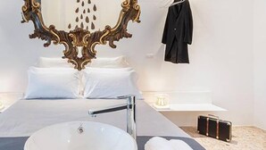 Una camera d'albergo moderna con un letto grande, un lavandino bianco e uno specchio con decorazioni elaborate.