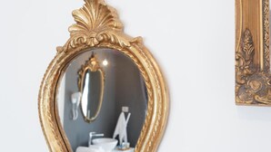 Un bagno con uno specchio dorato, un lavandino e un porta asciugamani.