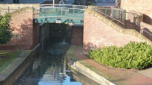 A canal with a bridge marked '165' and a brick building in the background.