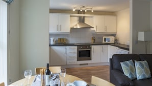 A modern kitchen with white cabinets, a stainless steel range hood, and a dining area with a table set for four.