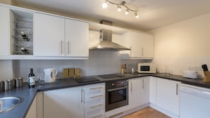 A modern kitchen with white cabinets, a stainless steel oven, a microwave, and a dishwasher.