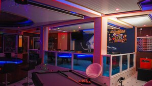 Een bar met een pooltafel, poolkeus en een roze stoel.