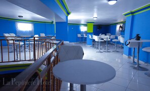 A hotel dining area with blue walls, white tables, and chairs.