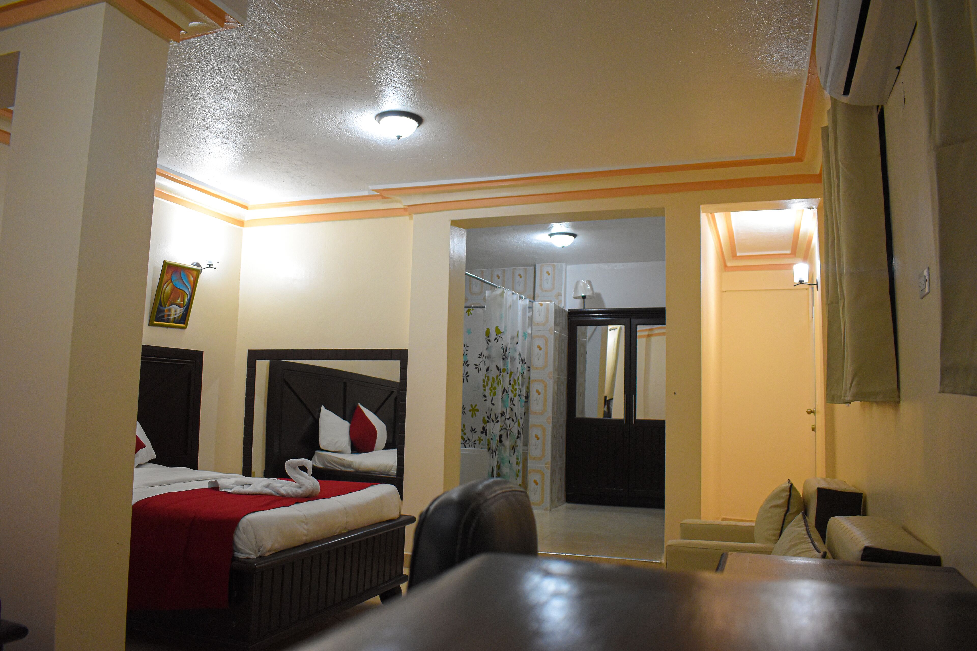 Une chambre d’hôtel avec deux lits, un espace douche et un coin salon.