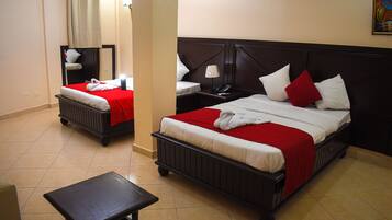 A hotel room with two beds, a nightstand, a table, and a mirror.