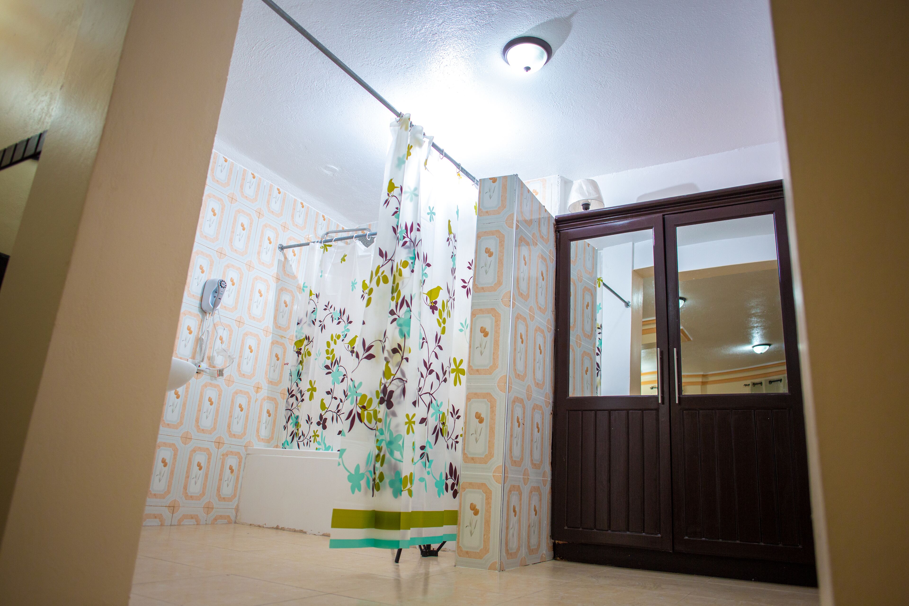 A room with patterned wallpaper, a curtain, a wooden door, and a ceiling light.