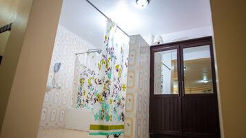 A room with patterned wallpaper, a curtain, a wooden door, and a ceiling light.