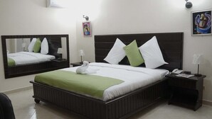 Een hotelkamer met een groot bed, een nachtkastje, een spiegel en een wandairconditioner.