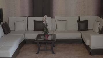 A modern living room with a sectional sofa, a glass coffee table, and a decorative plant.