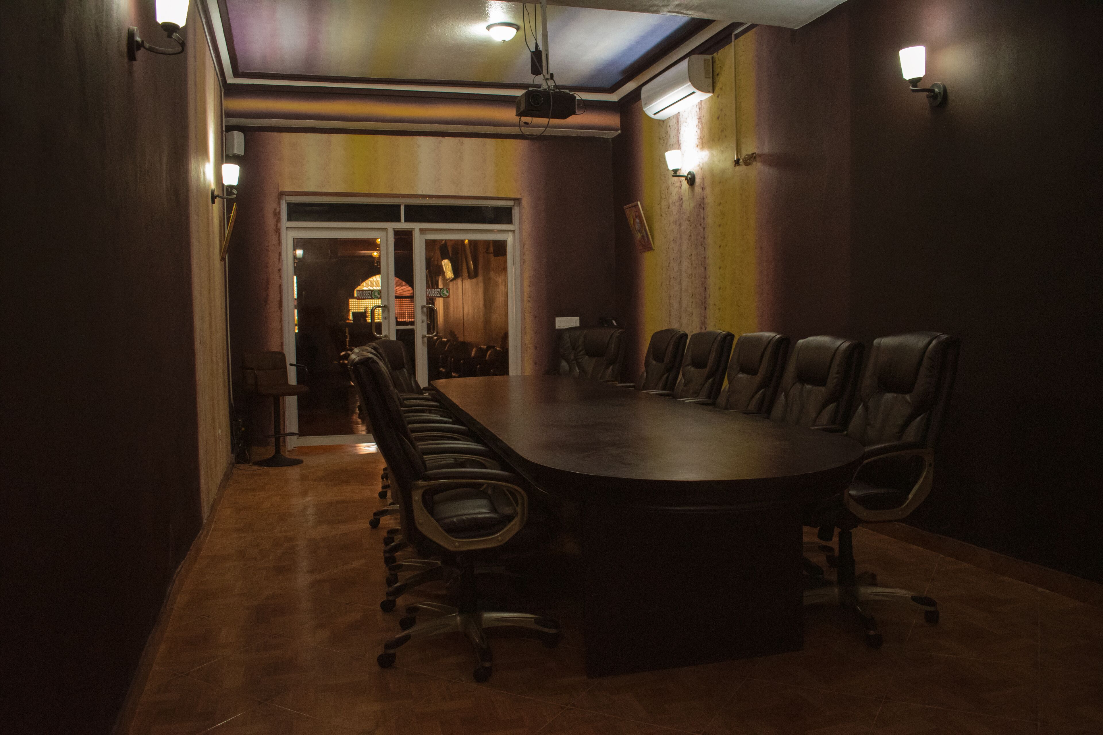 A conference room with a large oval table, leather chairs, and a ceiling-mounted projector.