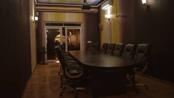 A conference room with a large oval table, leather chairs, and a ceiling-mounted projector.